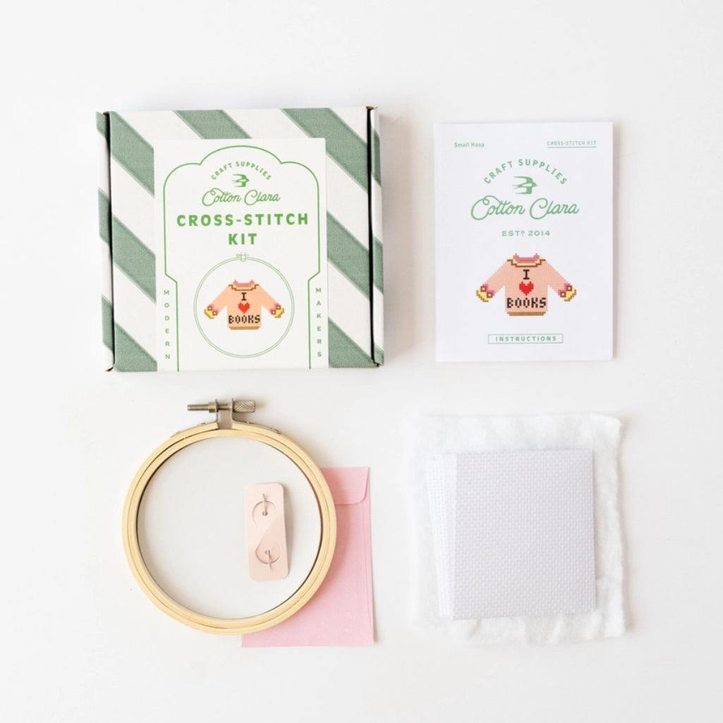 Cross-stitch kit with hoop, thread, and pattern on a white background
