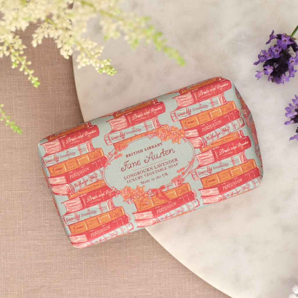 Soap bar with book-themed packaging on a textured surface with flowers