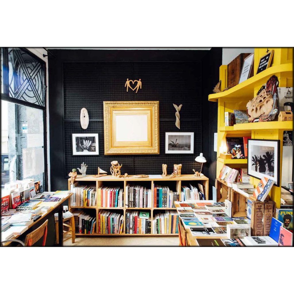 Bookstore interior with bookshelves, tables, and decorative items against a black wall.
