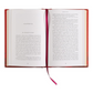 Open book with red binding and a pink ribbon on a white background