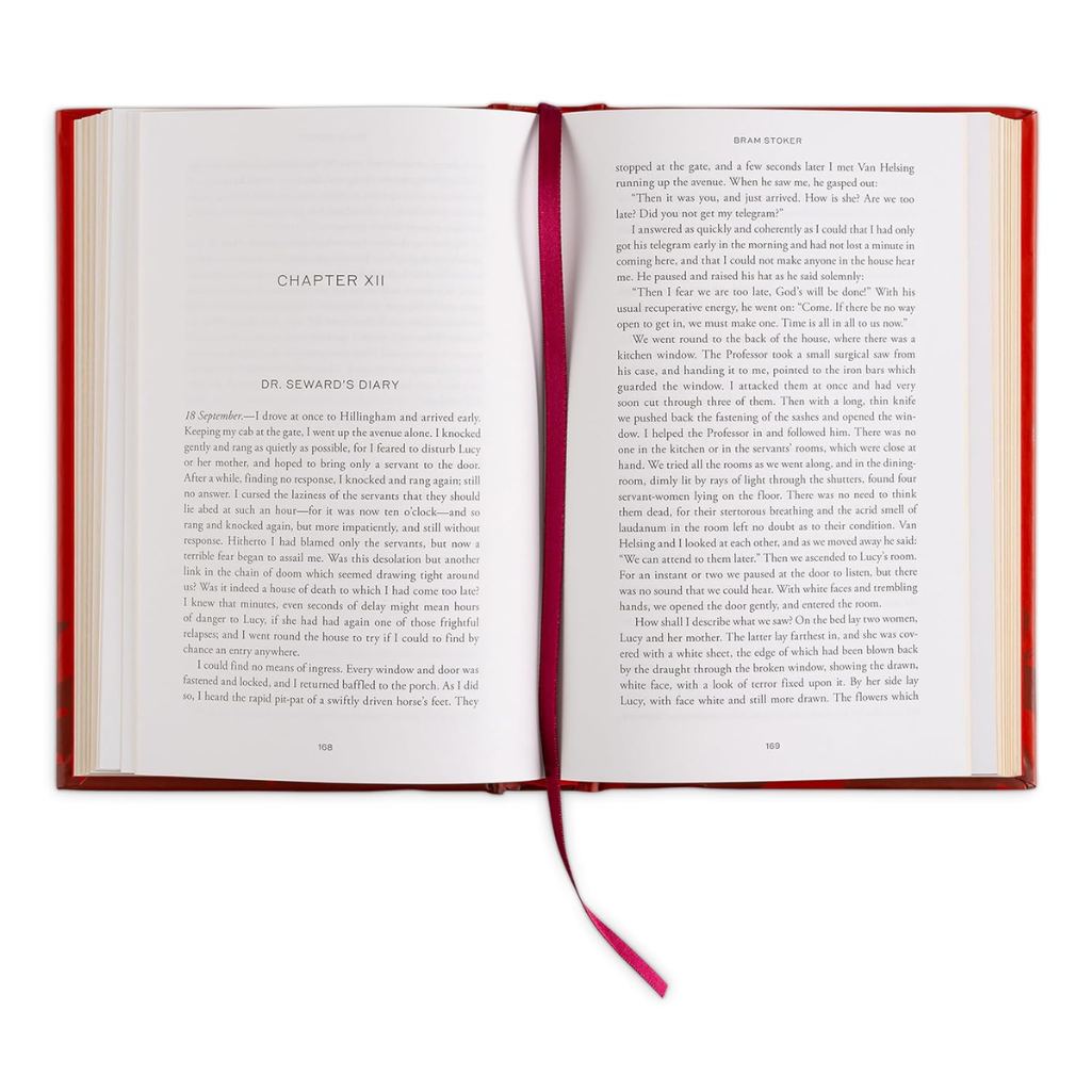 Open book with red binding and a pink ribbon on a white background
