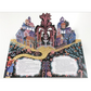 Decorative paper cutout with colorful houses and a fountain on a white background