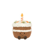 Plush toy shaped like a birthday cake with a candle on a light gray background