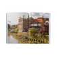 Open book showing a scenic view of a town with buildings and a river.