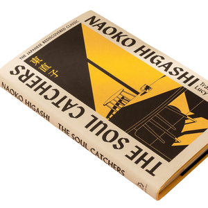 A hardcover book of The Soul Catchers by Naoko Higashi, featuring a cream-colored cover with bold black and yellow graphic design, photographed at an angle on a white background.