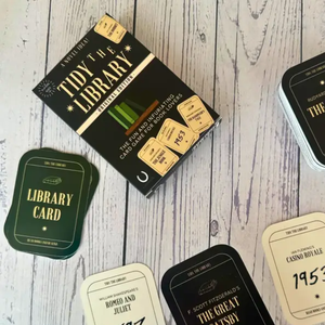 Collection of 'Tidy the Library' card packaging and cards on a wooden surface