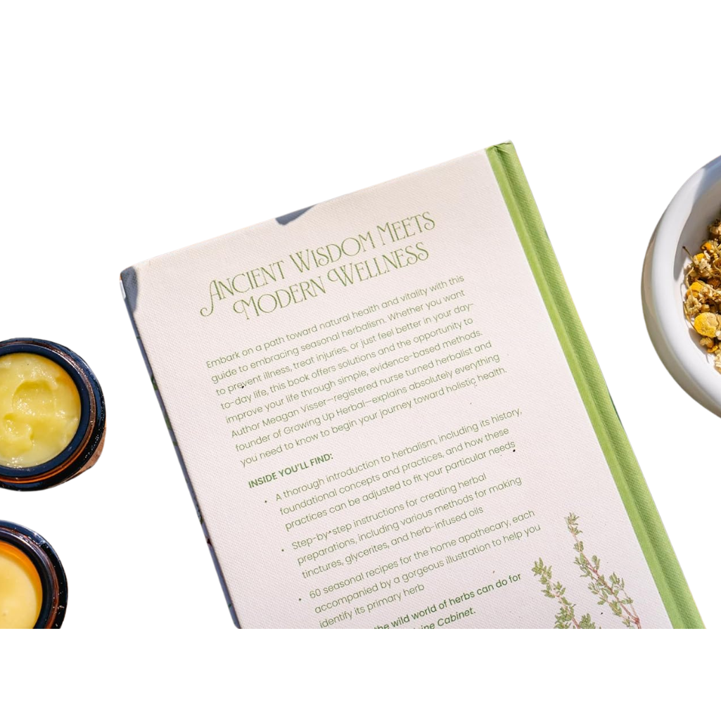 Book titled 'Ancient Wisdom Meets Modern Wellness' with a bowl of herbs and a jar of cream on a white background