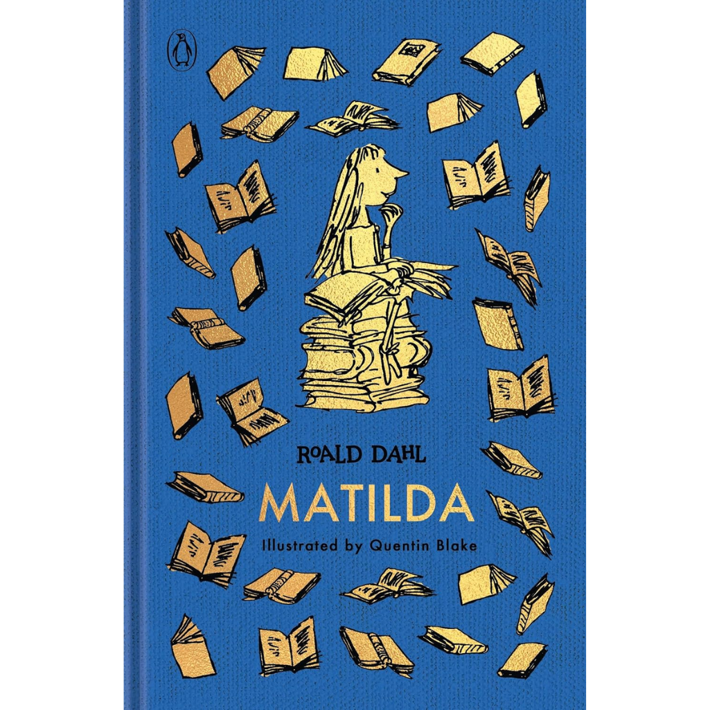 The front cover of the book 'Matilda' by Roald Dahl, illustrated by Quentin Blake, published by Penguin. The cover features a vibrant blue background with a central illustration of a girl sitting on a stack of books and surrounded by flying books, all in a yellow ink style.