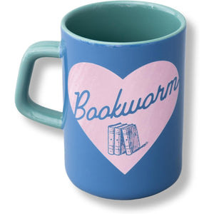 A blue ceramic mug with a mint green handle and interior, featuring a pink heart graphic on the front with the word 'Bookwarm' in blue script and an illustration of three books.