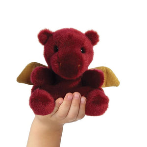 Red plush dragon toy held in a hand against