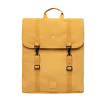 A mustard yellow backpack with a top handle, two front buckle straps, and a small square logo patch near the bottom, shown against a plain white background.