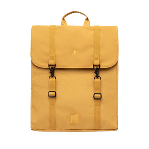 A mustard yellow backpack with a top handle, two front buckle straps, and a small square logo patch near the bottom, shown against a plain white background.