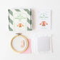 Cross-stitch kit with hoop, thread, and pattern on a white background
