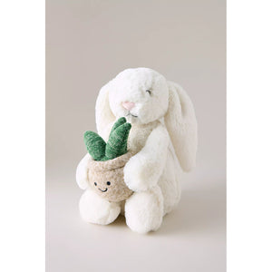 Plush toy rabbit holding a small plant on a plain background