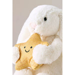White plush bunny holding a yellow star-shaped toy with a smiley face on a light gray background