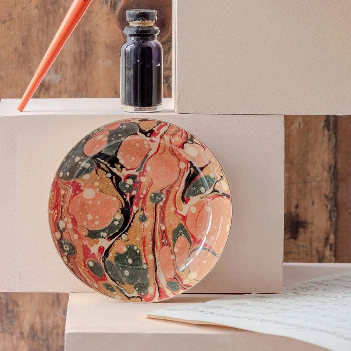 Marbled ceramic plate with a bottle of ink on a wooden surface