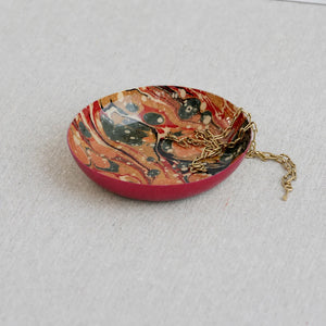 Marbled patterned dish with a gold chain on a light gray background