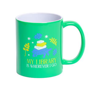 Green ceramic mug features a content tortoise calmly carrying a stack of books on its back, surrounded by foliage and stars. Beneath this cosy caravan of knowledge, the golden-yellow text reads: "My Library Is Wherever I Go"