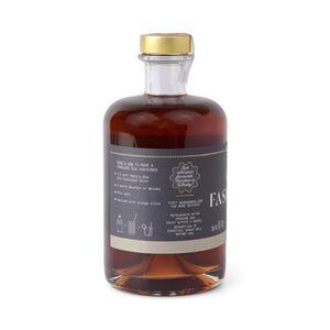 Bottle of old fashioned mixer with a gold cap on a white background