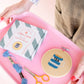 Cross stitch kit with hoop, threads, scissors, and pattern book on a pink tray.
