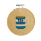 Cross-stitched tea can design in a wooden hoop on a white background
