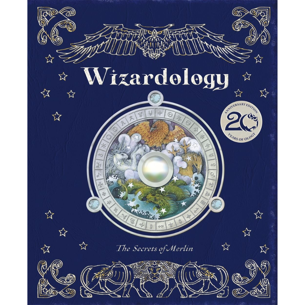 The front cover of the book 'Wizardology: The Secrets of Merlin' featuring a dark blue background with silver-toned ornate illustrations of an eagle, stars, and animals, plus a central circular illustration of Merlin and a glowing gem.