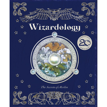The front cover of the book 'Wizardology: The Secrets of Merlin' featuring a dark blue background with silver-toned ornate illustrations of an eagle, stars, and animals, plus a central circular illustration of Merlin and a glowing gem.