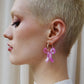 Woman wearing a pink bow earring with a neutral background