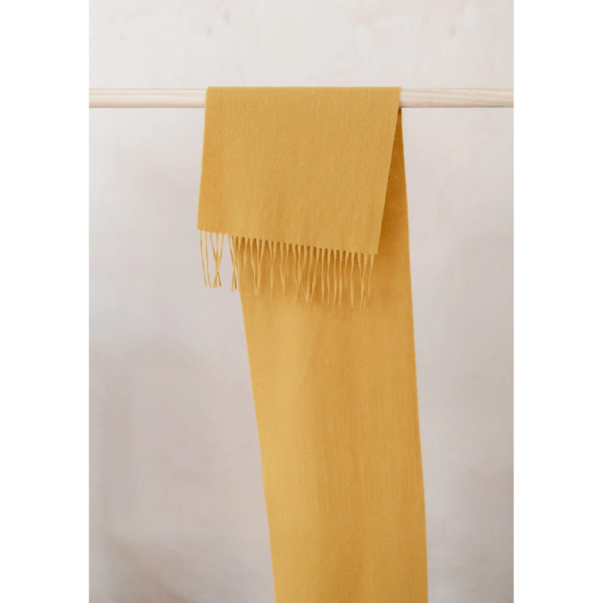 Mustard Lambswool Scarf hanging from pole